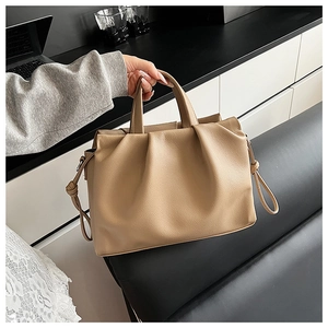 Detail of khaki pleated leather shoulder bag with lychee texture and sturdy handles