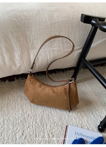 Détail du sac croissant en daim marron vintage montrant la texture mate et la fermeture