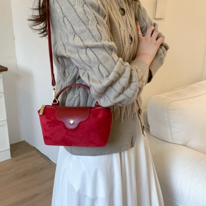Close-up of red suede and leather mini handbag with gold-tone hardware and top handle