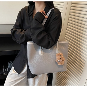 Macro detail of grey leopard embossed tote bag featuring a cute brown plush bear charm