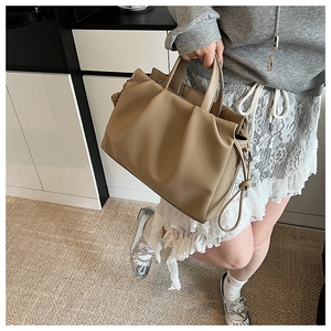 Detail view of khaki pleated tote bag with double handles shown on female model