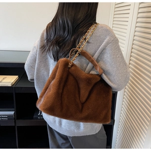 Detail of soft brown faux fur tote bag featuring a gold chain strap and leather handle