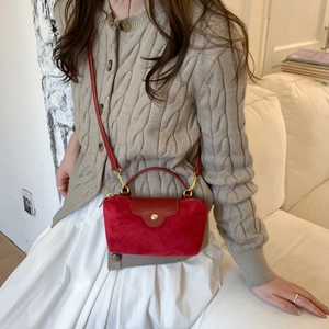 Red faux suede crossbody bag styled with knitwear showing the compact size and metal clasp