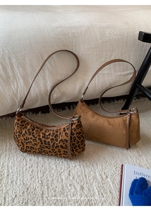 Détail de sacs croissants en daim léopard et beige sur un tapis moelleux en peluche