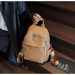 Detail of camel leather backpack with lychee texture and silver zippers on wooden stairs