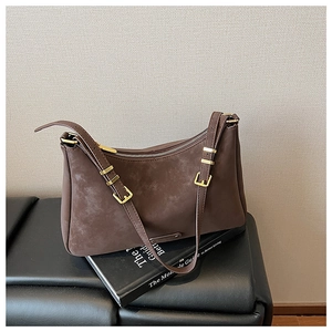 Detail of matte brown leather texture and golden buckle on the retro crossbody bag