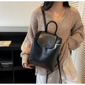 Détail du sac à dos en similicuir noir avec texte embossé et fermeture éclair latérale
