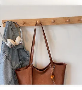 Close-up of retro brown leather tote with tassel detail and wooden beads on side