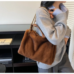 Detail of soft brown faux fur handbag with elegant gold metal chain shoulder strap