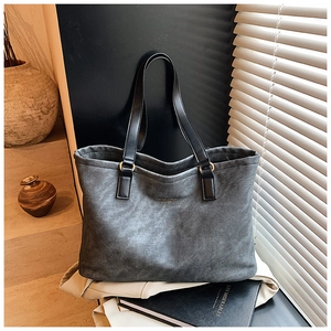 Close-up of textured canvas tote bag featuring gold lettering and leather straps
