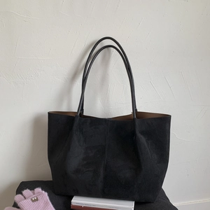 Macro detail of the black suede tote bag texture with minimalist vertical stitching