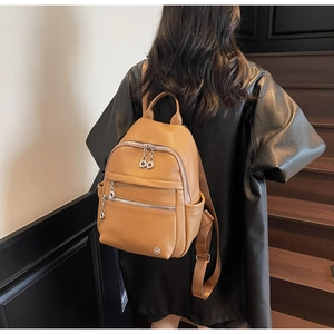 Close-up of brown faux leather backpack with metallic logo and multi-pocket design details