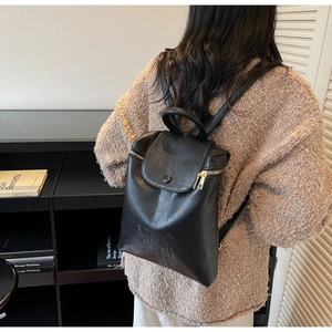 Détail du sac à dos vintage en cuir noir avec zip doré et logo embossé sur le bas