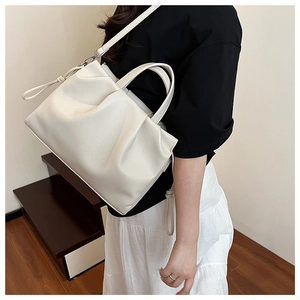 Detail of white pleated cloud bag with soft lychee texture leather and slim shoulder strap