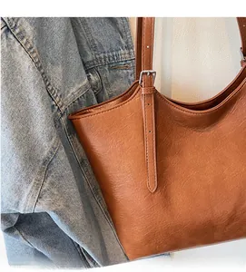 Detail of vintage brown leather tote bag with silver buckle and stitched texture