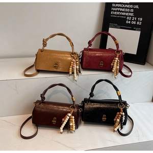 Detail of retro leather handbags with woven handles and tassel charms on marble