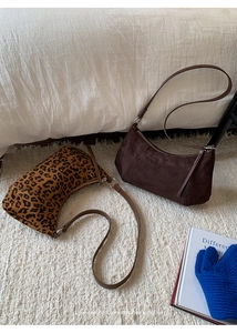 Détail du sac hobo léopard et du sac à bandoulière en daim marron sur tapis blanc