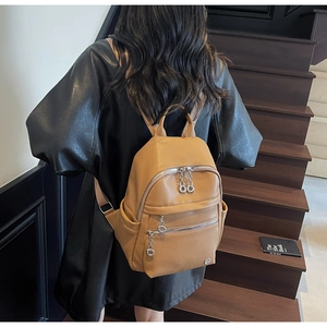 Rear view of model wearing a brown lychee pattern leather backpack with zippers