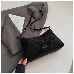 Detail view of black frosted suede shoulder bag with gold metal logo and zipper closure
