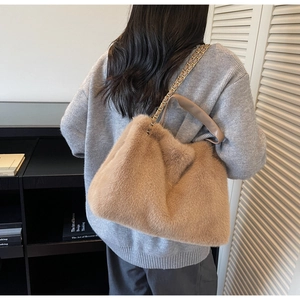Rear view of model holding a fluffy faux fur tote bag with gold chain and leather straps
