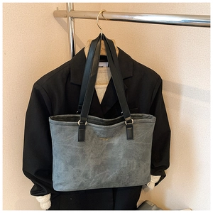 Detail of grey suede tote bag with black leather handles and fashion lettering print