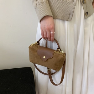 Close-up of contrast suede handbag with leather flap and golden metallic zipper detail