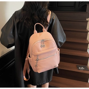Pink litchi leather backpack for women with silver zippers and round metal charm detail