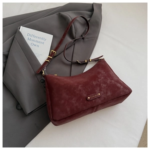 Detailed close-up of matte burgundy crossbody bag with gold logo and suede texture