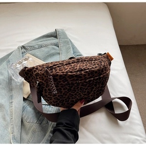Detail of leopard print crossbody bag with woven zipper pull and brown adjustable strap