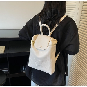 Détail du sac à dos en cuir crème avec double fermeture éclair dorée et texture gaufrée