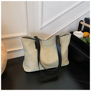 Detail of light green leather tote bag with gold lettering and black shoulder straps