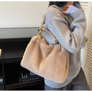 Detailed side view of a fluffy khaki plush tote bag with a gold chain strap on a model