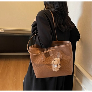 Detailed close-up of brown leopard print tote bag with plush puppy charm accessory