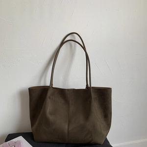 Detail of minimalist coffee brown suede tote bag featuring vertical stitching and long straps