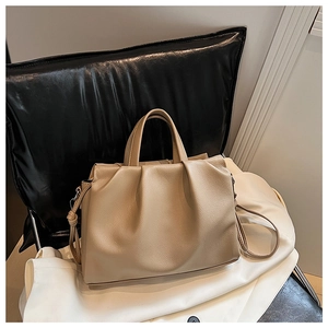Detailed macro view of beige pleated leather tote with silver metal hardware accents