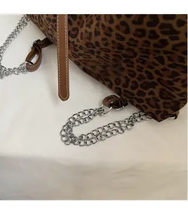 Detail of leopard print fabric with silver metal chain and brown leather strap finish