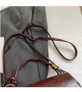 Detail of adjustable long shoulder strap and vintage gold hardware on brown leather bag