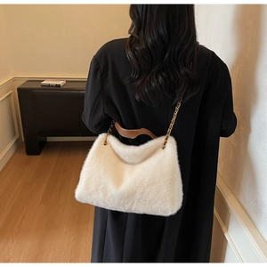 Detailed back view of a white plush tote bag featuring brown leather handles and gold chain