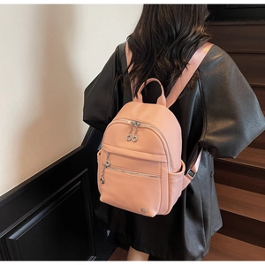 Detailed view of pink lychee texture leather backpack with silver zippers on a model