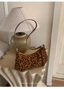 Gros plan d'un sac à main rétro léopard avec bandoulière sur un socle décoratif