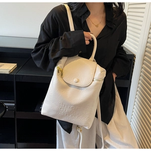 Vue détaillée du sac à dos blanc crème avec logo gaufré et texture en cuir souple