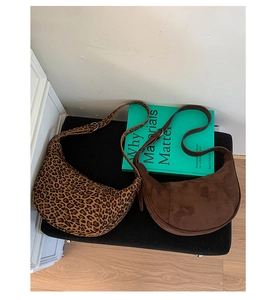 Detailed comparison of leopard print and dark brown half-moon hobo bags on a soft stool
