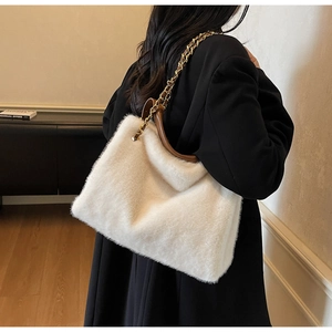Detailed close-up of white plush tote bag featuring brown handles and gold chain strap