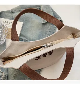 Detail of smooth metal zipper and brown canvas handle on a minimalist tote bag