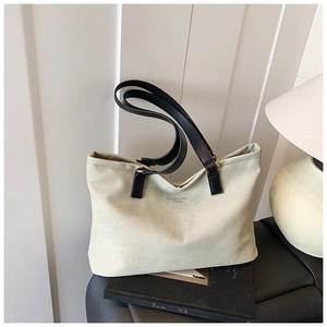 Detail of cream canvas tote bag with black leather handles and printed fashion text
