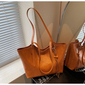 Detail view of brown vintage tote bag with pleated texture and ethnic beaded tassel