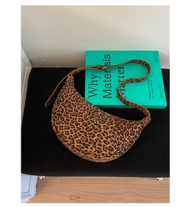 Dettaglio ravvicinato di una borsa a mezzaluna con stampa leopardata su panca nera