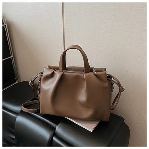 Detail view of brown pleated leather handbag with drawstring knots and silver zipper