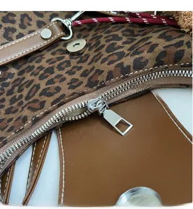 Detail view of smooth metal zipper and magnetic closure on leopard print tote bag