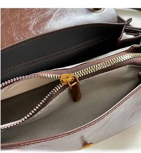 Detailed macro view of the smooth golden metal zipper and herringbone lining of the bag